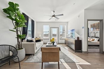 A living room with a white couch, a wooden table, and a ceiling fan.